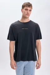 Camiseta negra de corte amplio con mangas cortas y estampado de un globo terráqueo en color naranja en la espalda, con la frase 'Respect the Earth'.