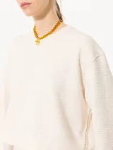 Buzo de punto color crema con lurex y mangas largas con puños ajustados.