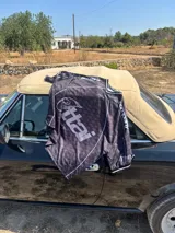 Camiseta negra con estampado de logos en gris y blanco, cuello redondo y mangas cortas. Diseño con ribetes blancos en cuello y mangas.