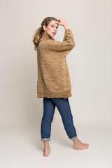 Tapado tipo poncho de tejido de punto grueso color beige, con cuello alto, cierre frontal con cremallera y bolsillos laterales.