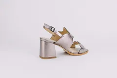 Sandalias plateadas de cuero con taco ancho y diseño de ondas en el empeine. Cierre con hebilla en el tobillo.