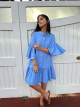 Vestido corto celeste de lino, con cuello mao, botones de nácar, mangas tres cuartos con volados y falda con volados.