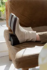 Bota corta de gamuza color beige claro, con caña ajustada y taco cuadrado de madera oscura.