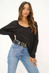 Buzo de tejido texturizado color gris oscuro, con escote en V, mangas largas, hombros caídos y aberturas laterales.