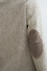 Chaqueta corta color marrón con cuello solapa y diseño con patchwork de telas. Manga larga con detalle de coderas aplicadas. Cierre frontal mediante botones y bolsillos ojal. Con forro.