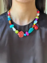 Collar corto con cuentas de cerámica, cristales checos y acrílico de diferentes colores y formas. Incluye una concha roja como dije central.