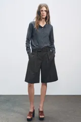 Chaqueta de punto fino color gris oscuro confeccionada con lana. Tiene cuello redondo, manga larga y cierre frontal con botones.