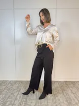 Blusa color beige de satén con escote en V y mangas largas.