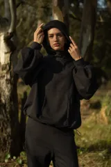 Canguro negro oversize de algodón, con capucha amplia, cuello alto integrado y ruedo ajustable con tancas.