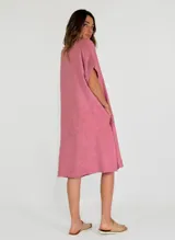 Vestido blanco de lino, corte recto, con cuello en V, mangas cortas con dobladillo y bolsillos laterales.