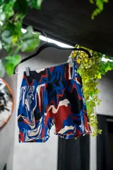 Calza corta deportiva con tiro alto y estampado abstracto en tonos rojo, azul, blanco y negro.