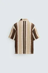Camisa de hombre de corte relajado, confeccionada en tejido de crochet con estructura abierta. Presenta cuello bowling, manga corta y cierre frontal con botones.