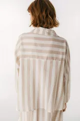 Camisa celeste y blanca a rayas verticales, de corte holgado y mangas largas.