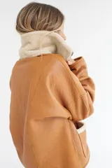 Buzo reversible de cuero genuino color beige, con cierre frontal parcial y bolsillos laterales con cremallera.