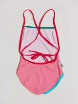 Traje de baño entero rojo con tirantes finos y espalda cruzada. Presenta un parche bordado con un monstruo en la parte inferior. Tiene ribetes en color borgoña y celeste en la parte superior, y ribetes en color naranja y verde en la parte inferior.