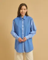 Camisa celeste holgada de manga larga con bolsillo en el pecho y cuello clásico.