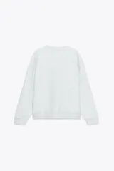 Sudadera gris melange de cuello redondo y manga larga con puños elásticos. Estampado frontal con texto "Chicago Harlem" y dibujo de Betty Boop.