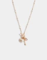 Collar de cadena corta dorada con dijes estilo vintage: corazón, llave, perla y cristal.