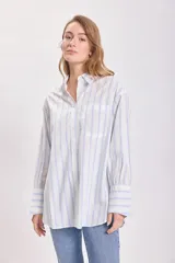 Camisa blanca con rayas verticales celestes, de corte clásico y manga larga.