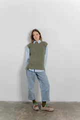 Chaleco de punto color crema con cuello alto y diseño de trenzas.