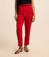 Pantalón de vestir color blanco, de corte carrot, con bolsillos laterales, pliegues frontales y cinturón fino de cuero sintético negro.