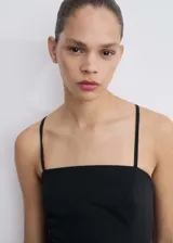 Vestido corto negro con tirantes finos cruzados en la espalda, diseño evasé y cuello escotado.