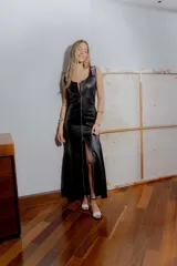 Vestido largo negro de cuero ovino con cierre frontal de cremallera metálica, sin mangas y con tajo lateral.