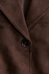 Blazer marrón oscuro con solapas de muesca, dos botones frontales y dos bolsillos de parche grandes en la parte inferior. Presenta canesú delantero y trasero y hombreras.