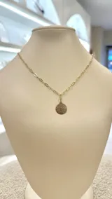 Collar dorado con cadena de eslabones rectangulares y dije redondo con la oración del Padre Nuestro grabada.