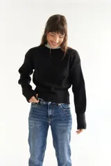 Sweater de punto negro con cuello alto y mangas largas.