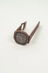 Reloj de pulsera negro con caja cuadrada y correa de silicona con hebilla.