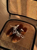 Zueco de cuero color marrón con cordones y suela de goma.