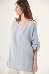 Blusa celeste de lino, corte holgado, cuello redondo y mangas 3/4 con botón.