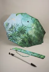 Sombrilla con estampado de hojas de palmeras y vegetación selvática en tonos verdes y celestes. Incluye funda con correa para transportar. Marca BT Merch.