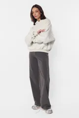 Buzo tipo hoodie color beige, de frisa gamuzada, con silueta oversize, bolsillo canguro, puños y cintura de ribb, capucha forrada con jersey y aplique de ojalillos en los puños.