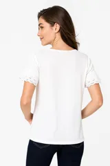 Remera blanca de manga corta con cuello redondo y calado en el frente.