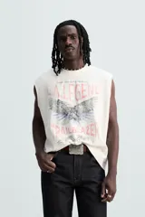 Musculosa blanca con efecto lavado, cuello redondo y sisa ancha. Estampado frontal con la leyenda "L.A. Legend Trailblazer" y un águila.