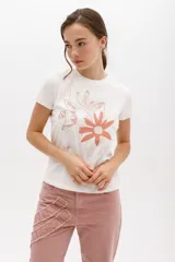 Remera blanca de algodón con estampado de dos flores en tonos naranja y beige.