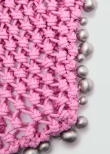 Bolso shopper tejido de color rosa con abalorios plateados en el borde y en las asas.