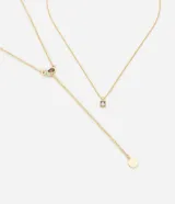 Collar dorado de metal con dos cadenas de diferente largo. La cadena más corta tiene un dije cuadrado con una piedra blanca. La cadena más larga tiene dos piedras de colores y un dije redondo liso.