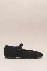 Zapato tipo Mary Jane de cuero vacuno color negro, con punta redondeada, correa con hebilla y suela de cuero.