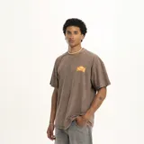 Remera marrón de corte holgado con cuello redondo y estampado pequeño en el pecho con el logo de la marca Pulau.