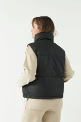 Chaleco puffer color verde oliva con cuello alto y cierre frontal con cremallera.