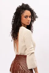 Vestido corto color crema, tejido de punto con lurex, escote redondo y mangas largas acampanadas.