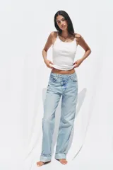 Pantalón de jean celeste de tiro alto, corte recto y largo hasta el tobillo con dobladillo. Tiene cinco bolsillos y cierre frontal cruzado con cremallera y botón.
