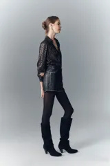 Short de cuero negro con tachas metálicas en ruedo, laterales y presillas.
