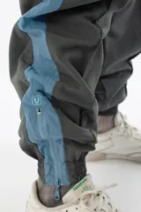 Pantalón de jogging gris con forro interno de red, bolsillos laterales con cierre, cierres en los tobillos y logo bordado.