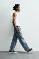 Pantalón de jean gris oscuro, corte amplio, con cinco bolsillos, efecto lavado y cierre frontal con cremallera y botón.