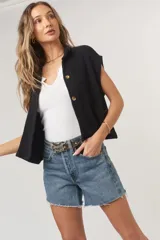 Camiseta negra con textura acanalada, corte holgado y cuadrado, cuello en punta, bolsillos amplios y botones funcionales.