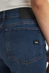 Jean de mezclilla azul oscuro, tiro alto, con corte acampanado (estilo Oxford o bootcut) y roturas sutiles en los muslos.